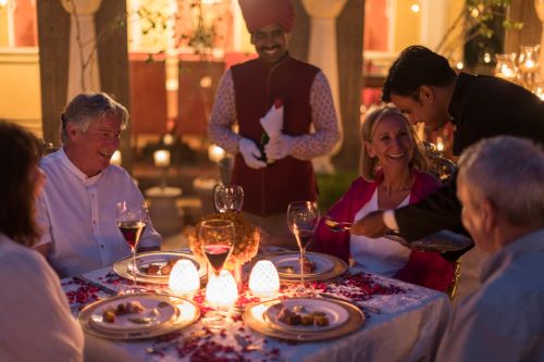 Two couples having a magical, traditional Indian dinner at a beautifully set table.
