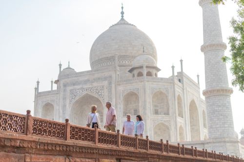 Two couples walking around the grounds of the Taj Mahal which is visible in the background.