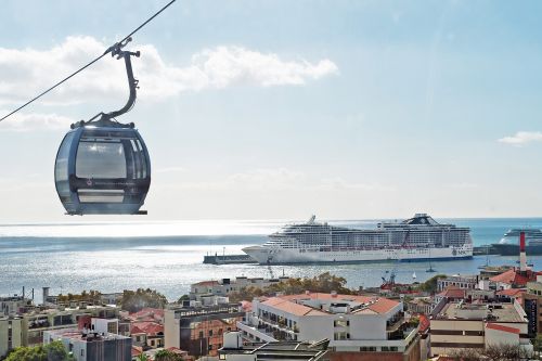 MSC Cruises ship docked in port with a cable car overlooking the waterfront.