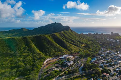 Aerial view of a volcanic crater in Honolulu with lush green ridges and the Pacific Ocean in the background