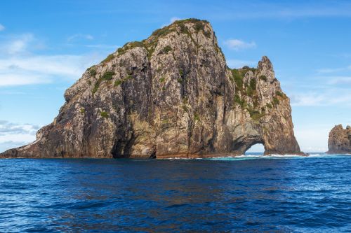 Rock island with a natural arch rising from the ocean.