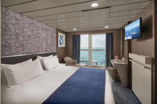 Cruise ship balcony cabin with double bed and ocean view.