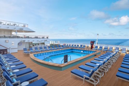 Cruise ship pool deck with lounge chairs overlooking the sea.