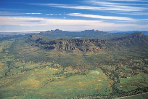 An aerial view of Wilpena Pound, a rock formation of a natural amphitheatre surrounded by green bushland 