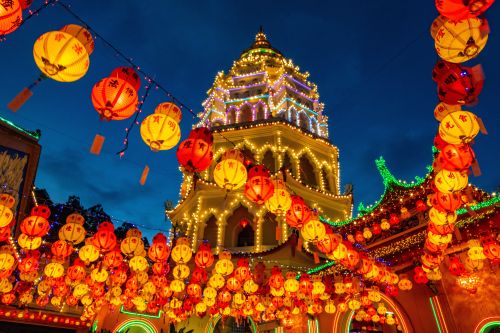 Lantern‑lit temple tower glowing at night with strings of red and yellow lanterns