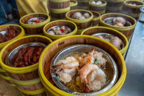 Steaming dim sum dishes arranged in round wooden baskets.