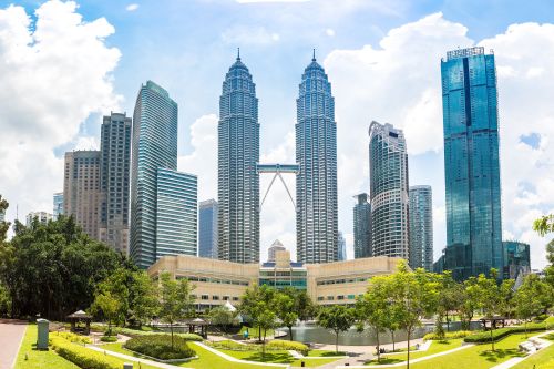 Twin skyscrapers rising above a park with gardens and ponds