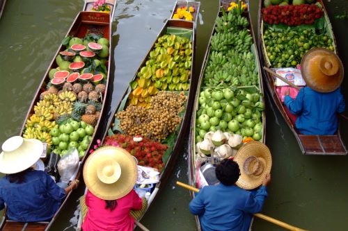 Long boats in the water with local Thai people selling their fresh produce 