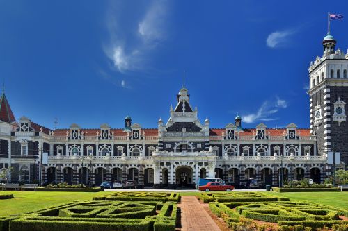 Historic Dunedin Railway Station with ornate façade and formal gardens in front.