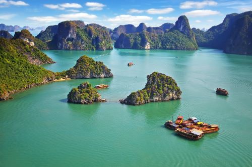 A group of islands in Ha Long Bay with some long boats 