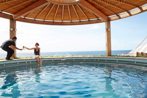 A passenger sitting by the pool while a waiter is offering her some water