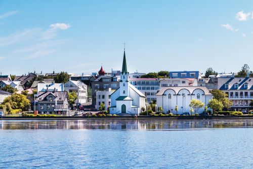 City waterfront with a white church and buildings reflected in calm water