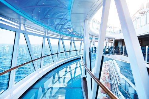 An enclosed glass hallway onboard a cruise ship which juts out over the ocean