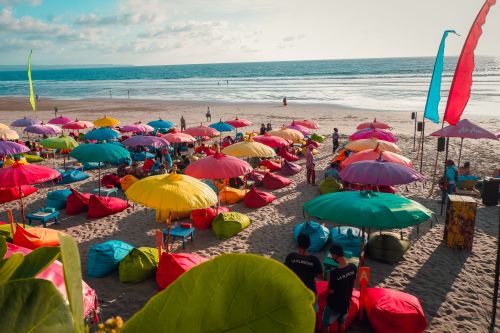 Brightly coloured umbrellas and beanbags set up along a sandy beach at sunset