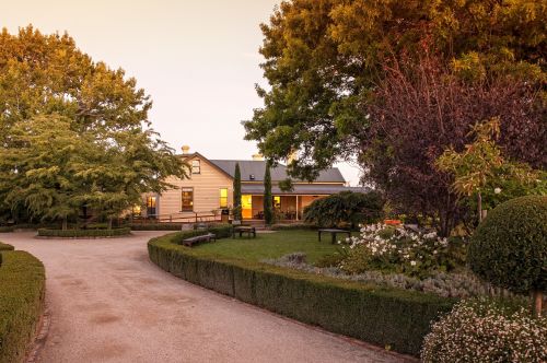 Entrance to Josef Chromy winery surrounded by a lush garden with trees and bushed and the main building in the backgorund