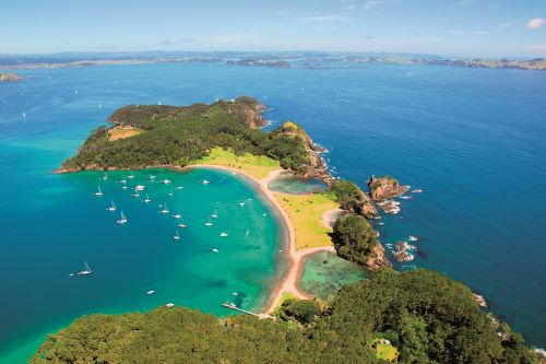 Aerial view of a sunny bay with lots of sailing ships anchored in the turquoise waters