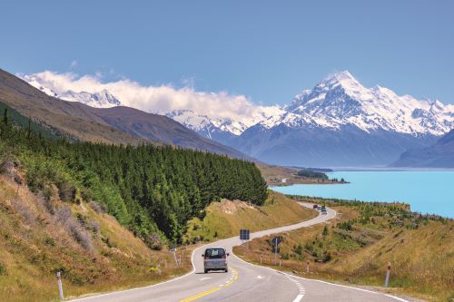New Zealand's windy roads leading car through picturesque lake and mountain landscape