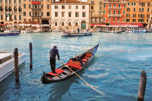 A gondolier manoeuvrings a gondola in the canals of Venice