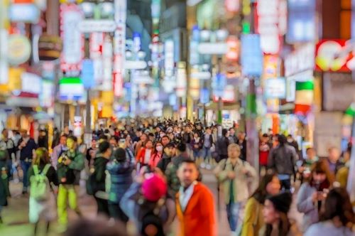 A bustling pedestrian street in Tokyo at night with neon-signs and people everywhere.