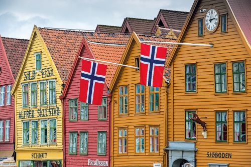 Row of colorful wooden buildings with Norwegian flags in Bergen, Norway