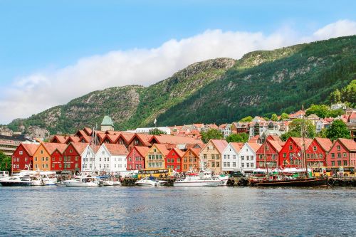 a row of typical Norwegian houses along the river with green mountains in the background