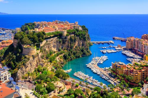 Aerial view of Monte Carlo with a cliffside old town and a marina filled with yachts