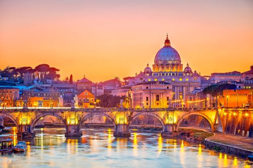 St. Peter's Basilica in Rome beautifully illuminated at sunset, with its grand dome standing out against the colourful sky.