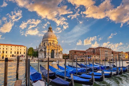 Row of gondolas on the Grand Canal with the domed Basilica di Santa Maria della Salute at sunset