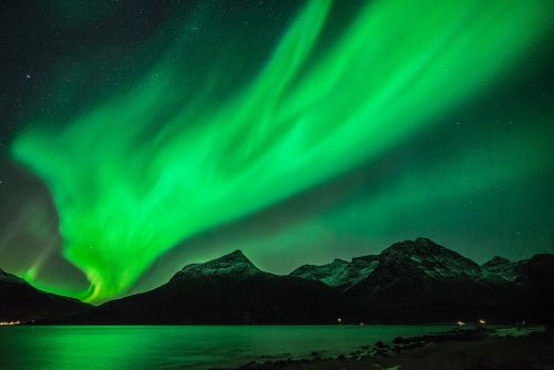 Green Northern Lights illumination the night sky and reflecting a lake in Norway