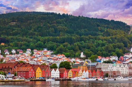 Typical Scandinavian buildings along the waterfront with a hilly forest in the background