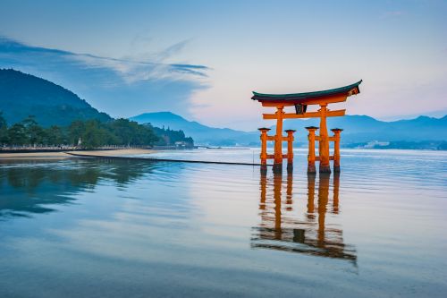 The iconic floating torii gate of Miyajima reflected in calm waters at dusk.