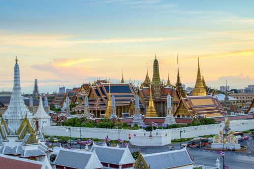 A temple featuring gold architecture and a white wall surrounding