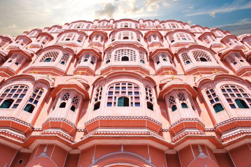 A low angle shot of the majestic Hawa Mahal palace built of red and pink sandstone featuring many small windows called decorated with intricate latticework.