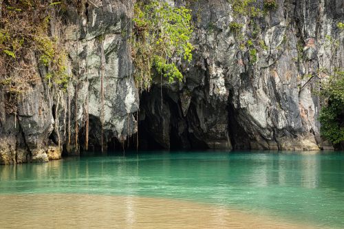 Entrance to Palawan's Underground River, framed by limestone cliffs and turquoise water.