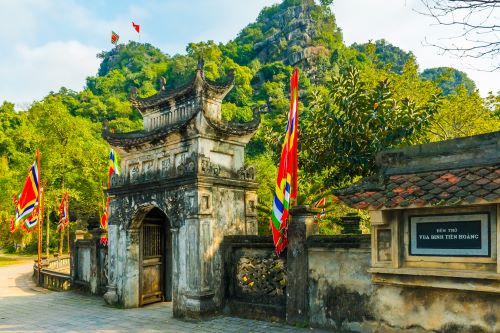 Traditional Vietnamese entrance of King Dinh Temple featuring intricate carvings and colourful ceremonial flags.